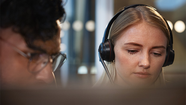 En mann og en kvinne sitter i et kontorlandskap med headset.