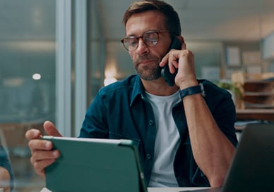 Mann snakker i telefonen og ser på pc