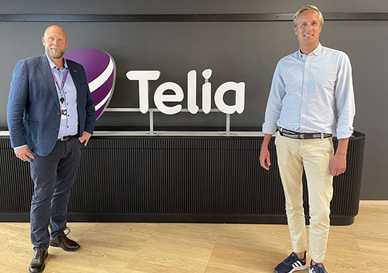 2 menn poserer foran en vegg med Telia logo