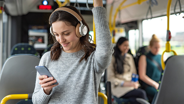 en dame ser på mobilen og står i en buss