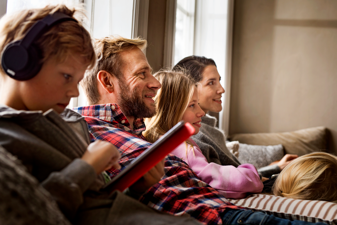 En liten familie sitter i sofaen og ser i samme retning