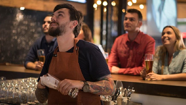 Mennesker i en bar ser opp mot en TV-skjerm