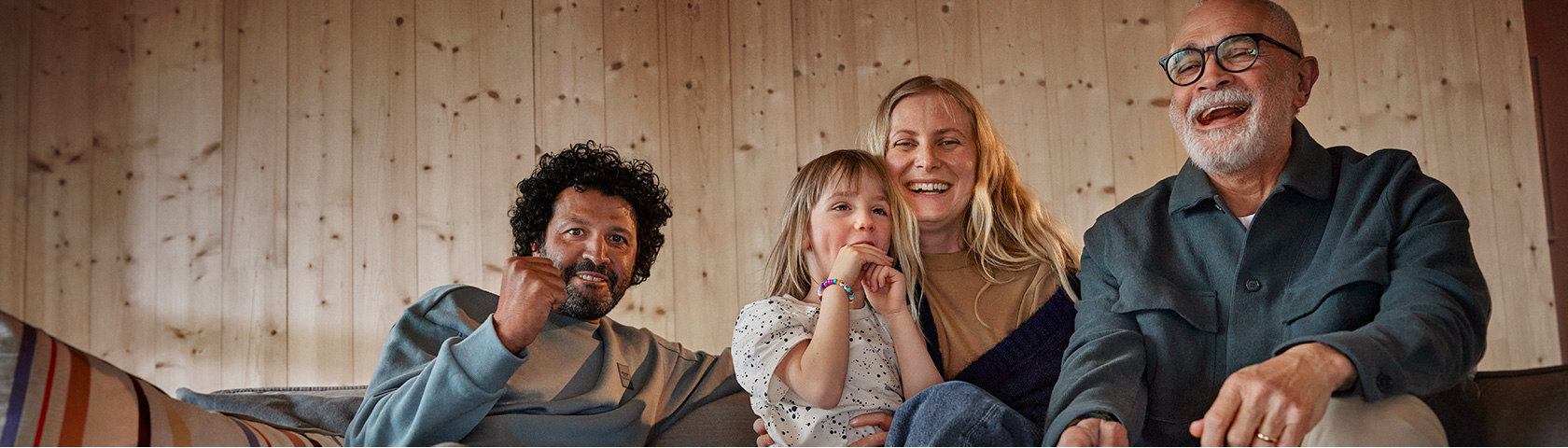 Familie koser seg i sofaen foran TV-en.
