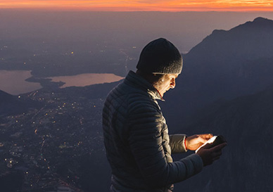 mann på tur på fjellet og ser på mobil