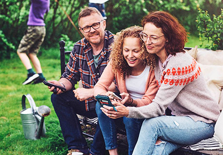Familie i hagen ser på mobilen sammen