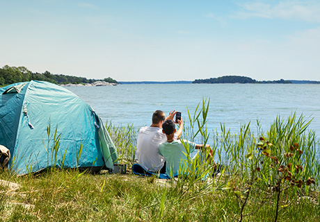 Kids ved teltet tar selfie med sjøen i bakgrunnen