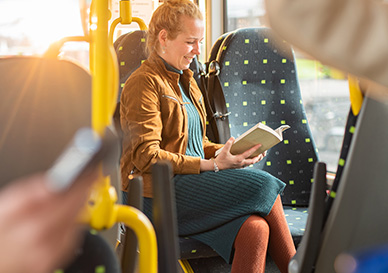 dame sitter i bussen og leser en bok