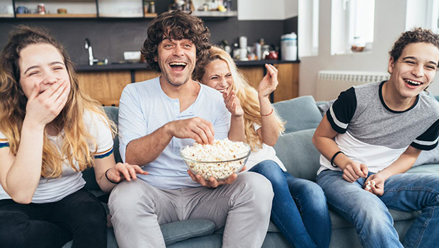 Fire mennesker i sofaen koser seg og ser TV