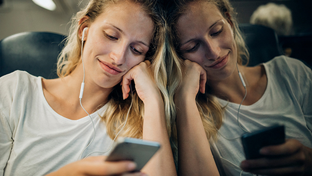 Ung kvinne sitter på toget og ser på mobilen