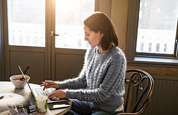 Dame sitter på hjemmekontor med laptop