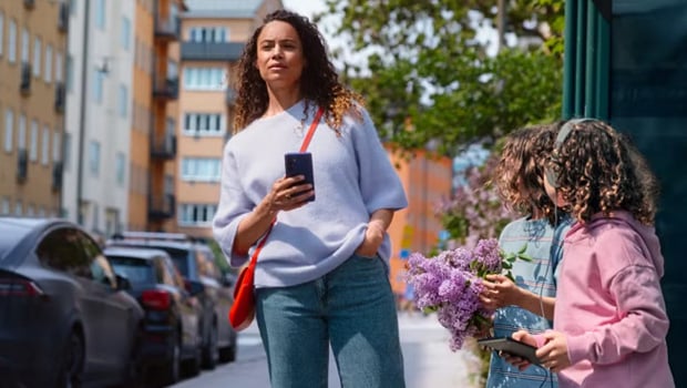 en dame på bussholdeplass og holder en mobil