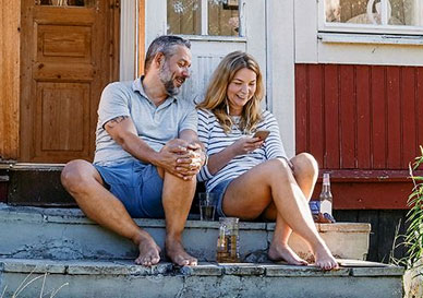mann og dame sitter på en trapp foran huset og surfer på mobil