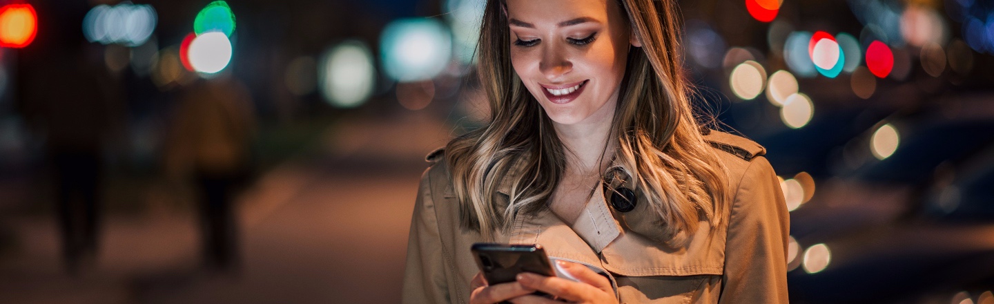 Dame i bybilde ser på mobilen sin