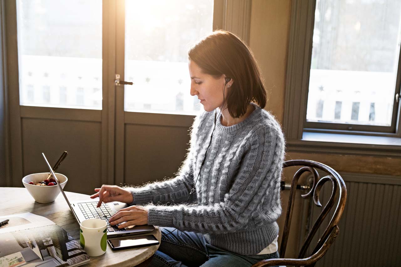 Kvinne sitter ved laptopen på hjemmekontoret.