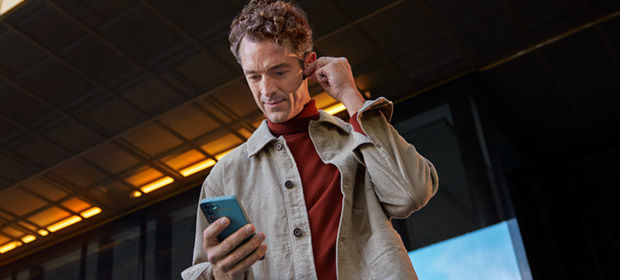 En mann ser på mobilen og har på headset.
