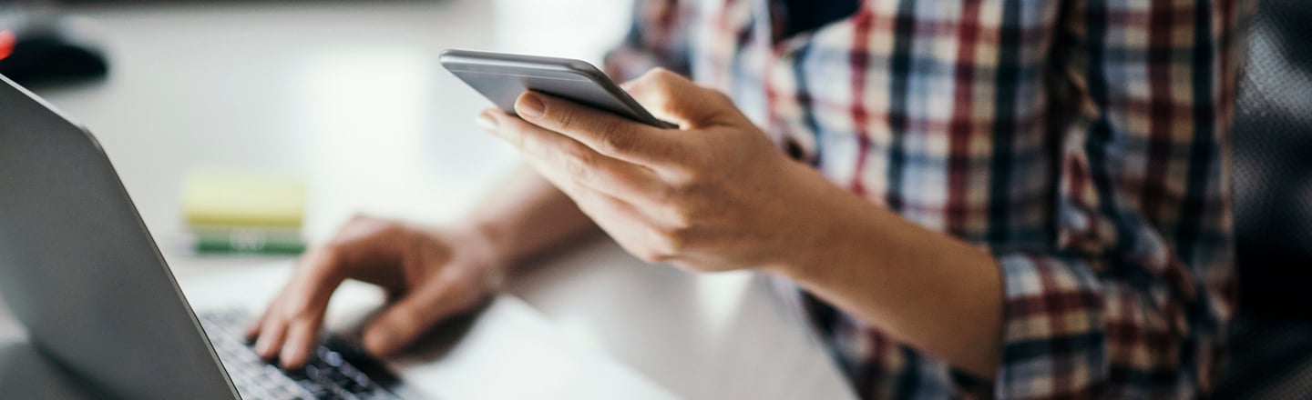 Kvinne på kafé med mobiltelefon og bærbar PC