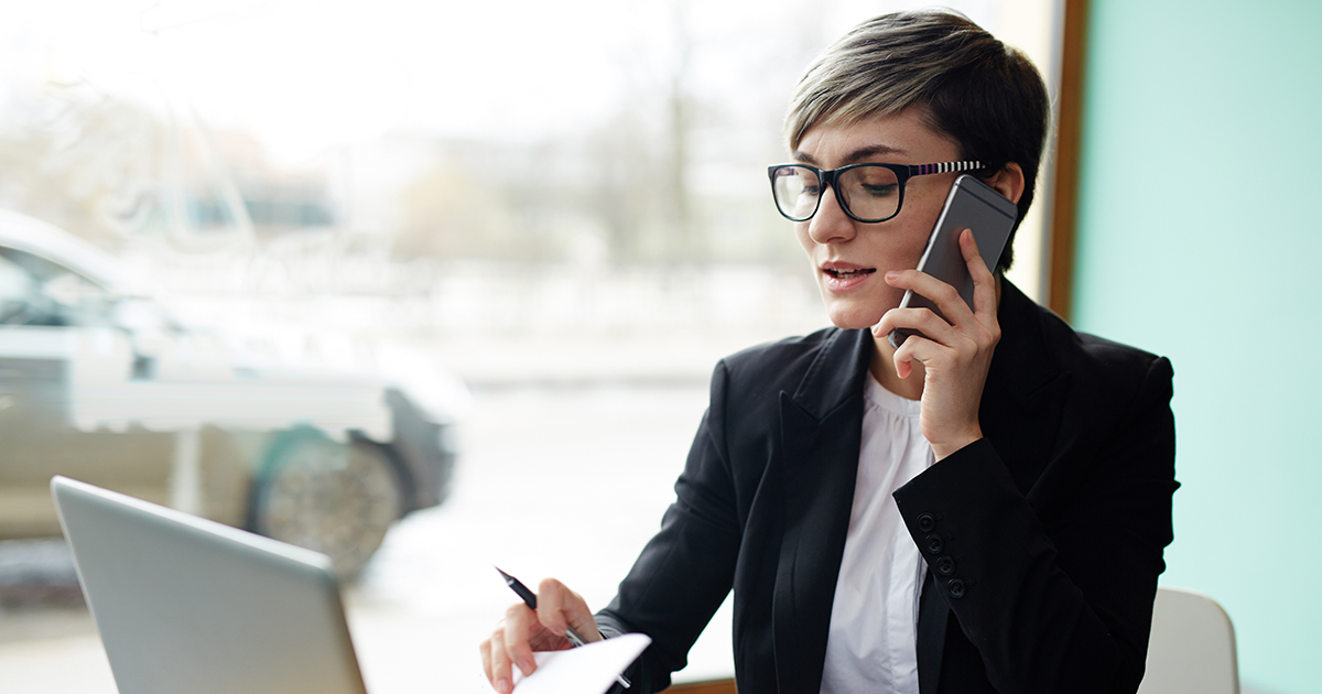 Kvinne på kafé med mobiltelefon og bærbar PC