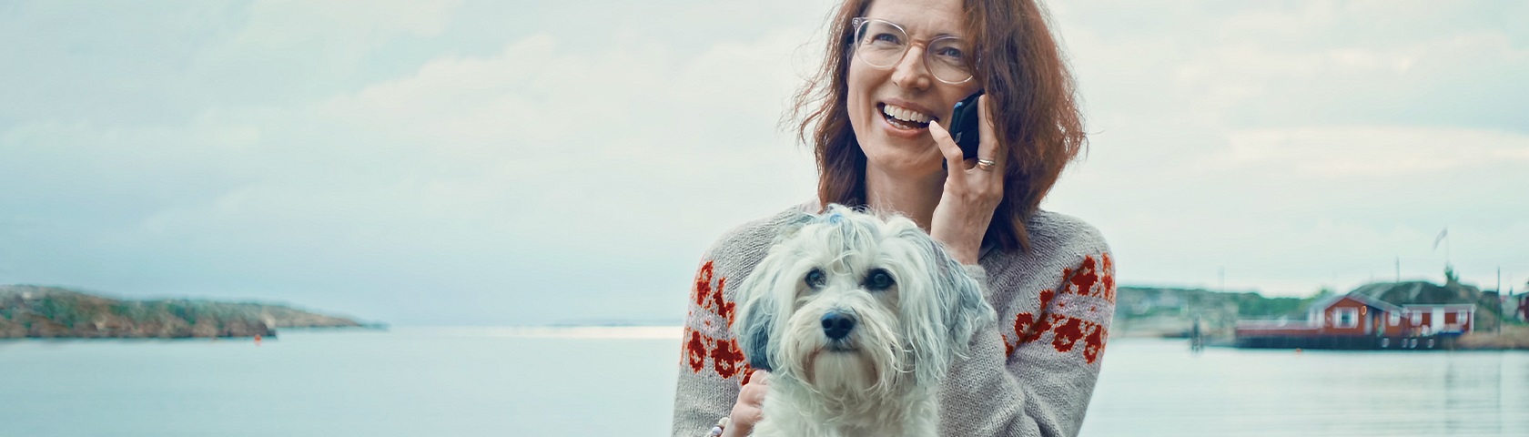 Dame med mobiltelefon og hund ved havet