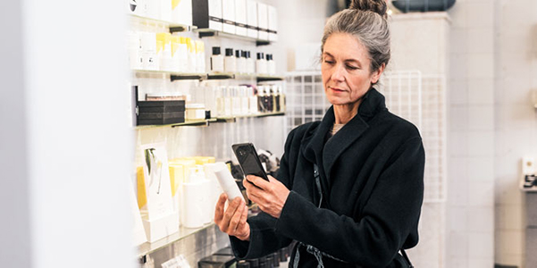 Kvinne i en butikk ser på mobilen sin.