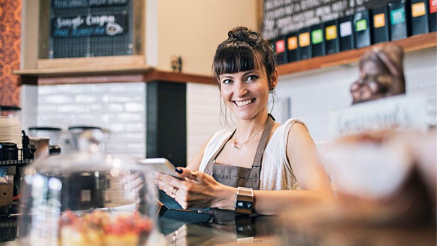 En smilende kvinne bak disken på en kaffebar