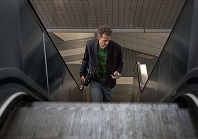 mann tar rulletrapp og ser på mobilen