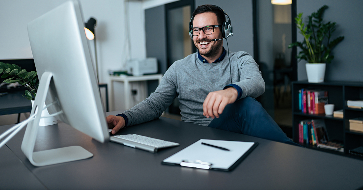 Mann på hjemmekontor med headset deltar i digitalt møte.