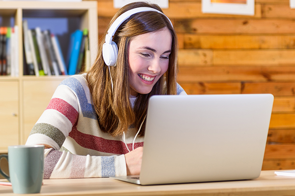 Kvinne med headset foran en pc deltar i fjern-møte fra hjemmekontor