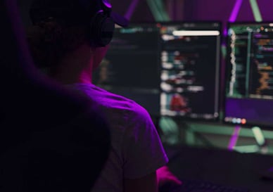 dame med headset ser på pc skjermer