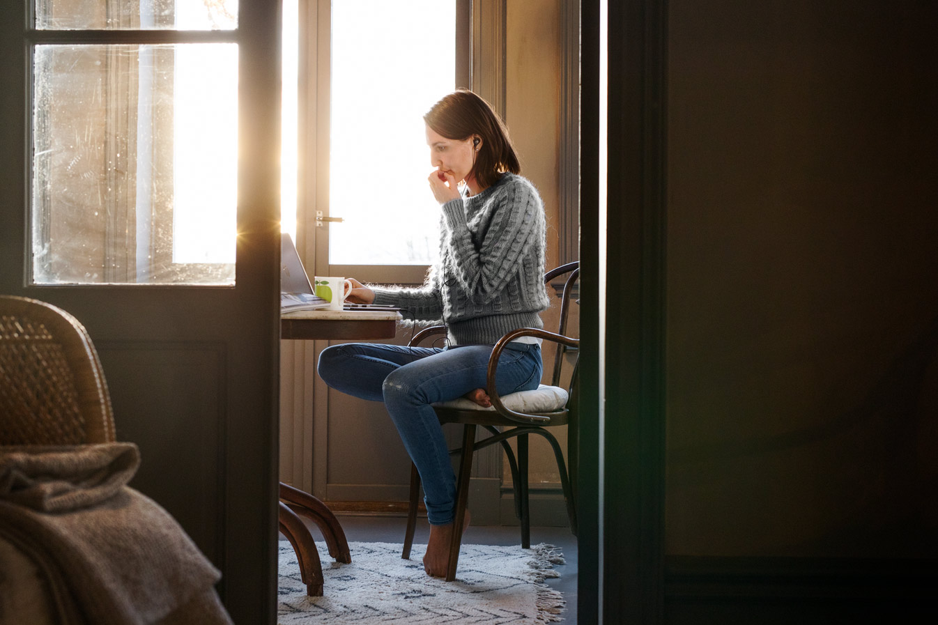 Tre unge menn sitter i sofaen og smiler/ler. De ser sammen på noe på en laptop.