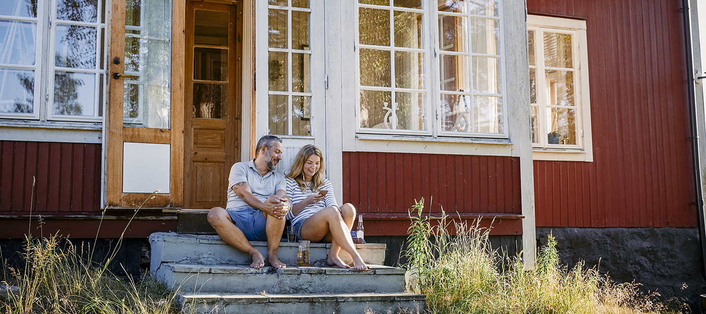 Par sitter med mobilen på hytta