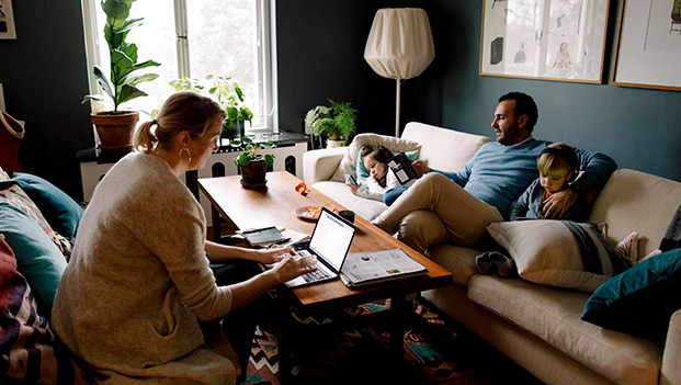 Familie i stua med laptop og mobil