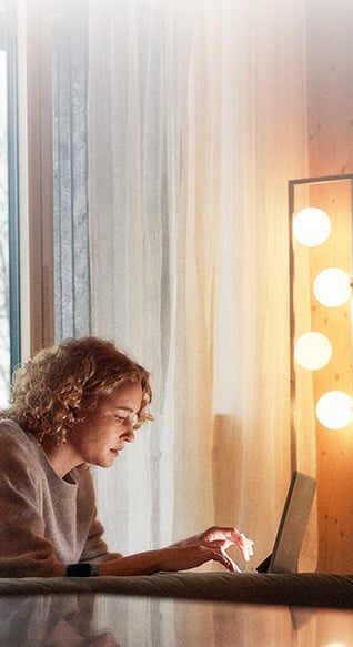 Ung kvinne ligger på gulvet og ser på laptopen.