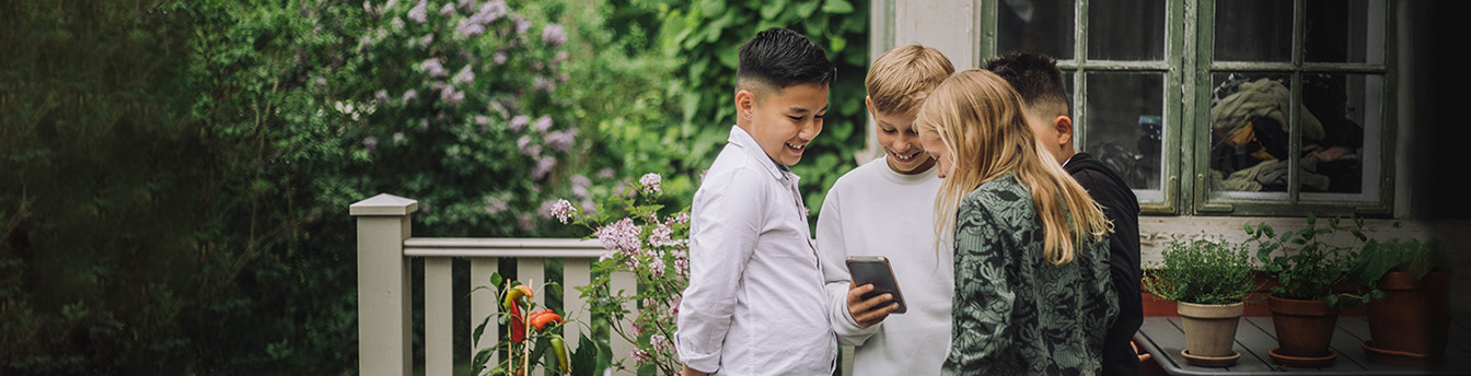 En gjeng med barn står på terrassen og ser på en mobil