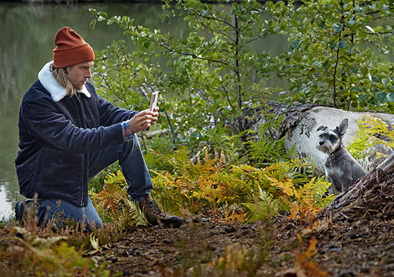 Mann og hund på tur i skogen, hunden poserer og blir avfotografert.