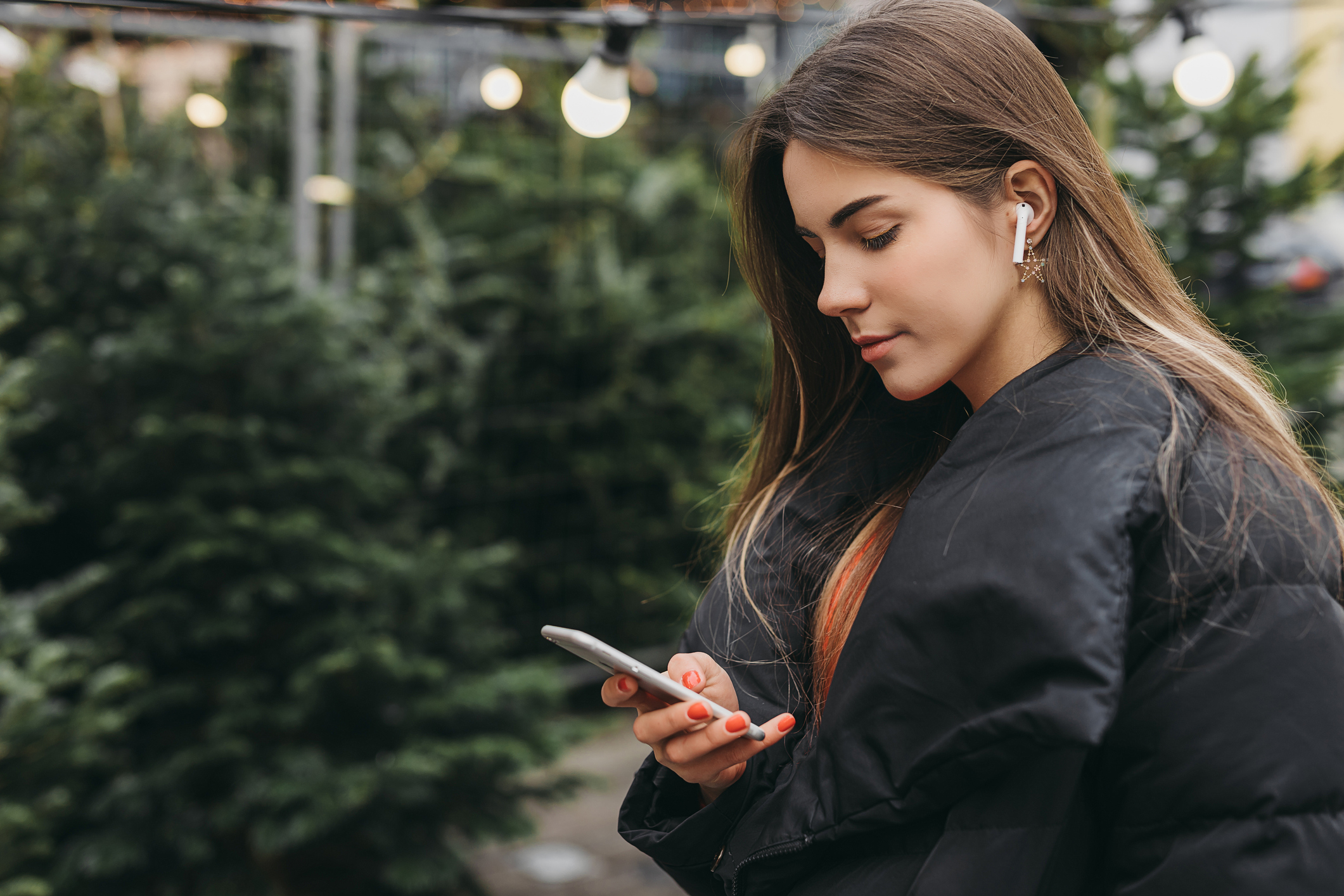 Jente er ute med telefon og airpods. Jente er ute med telefon og airpods.