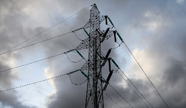 Strømmast med delvis skyet himmel i bakgrunnen.