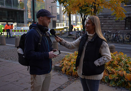 En kvinne intervjuer en mann på gata