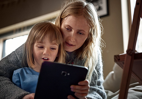 En jente og en kvinne sitter sammen og ser på en ipad