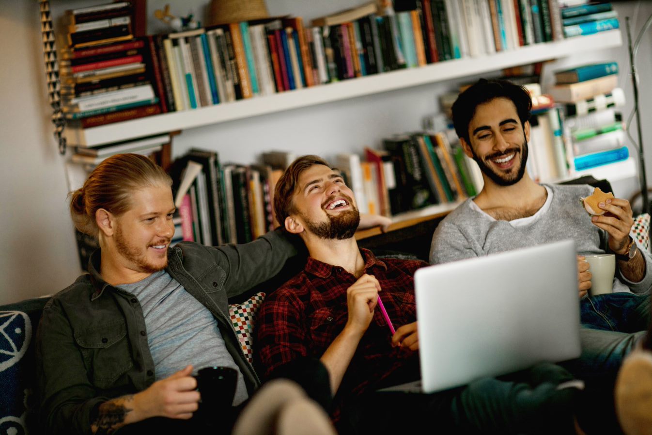 Tre menn i en sofa med en bærbar datamaskin