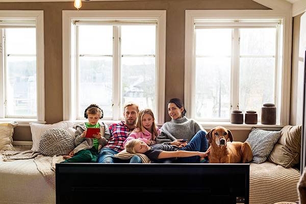 Familie med hund i sofaen foran TV-en.