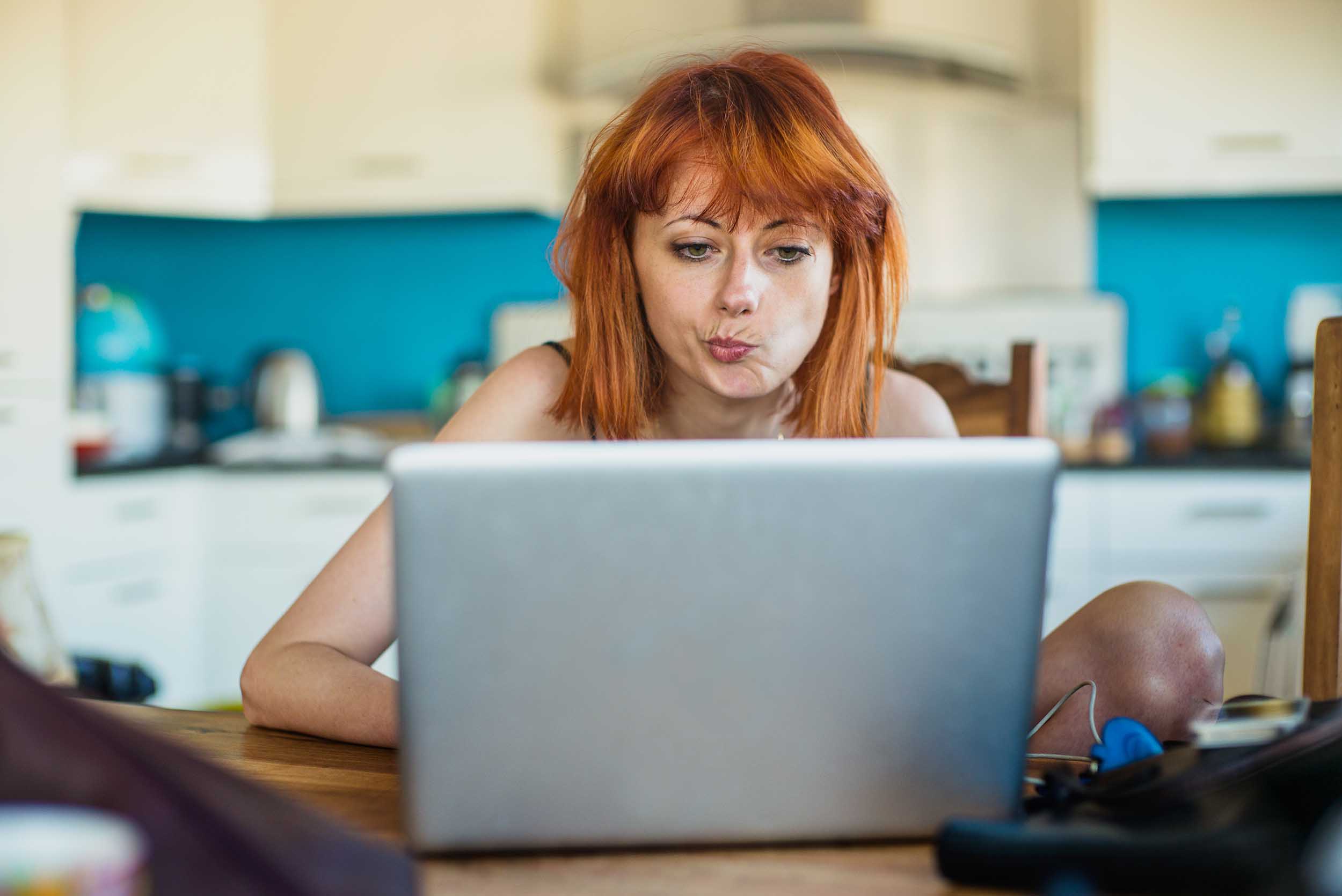 Bilde av en ung dame som sitter ved kjøkkenbordet og leser fra en PC. Bilde av en ung dame som sitter ved kjøkkenbordet og leser fra en PC.