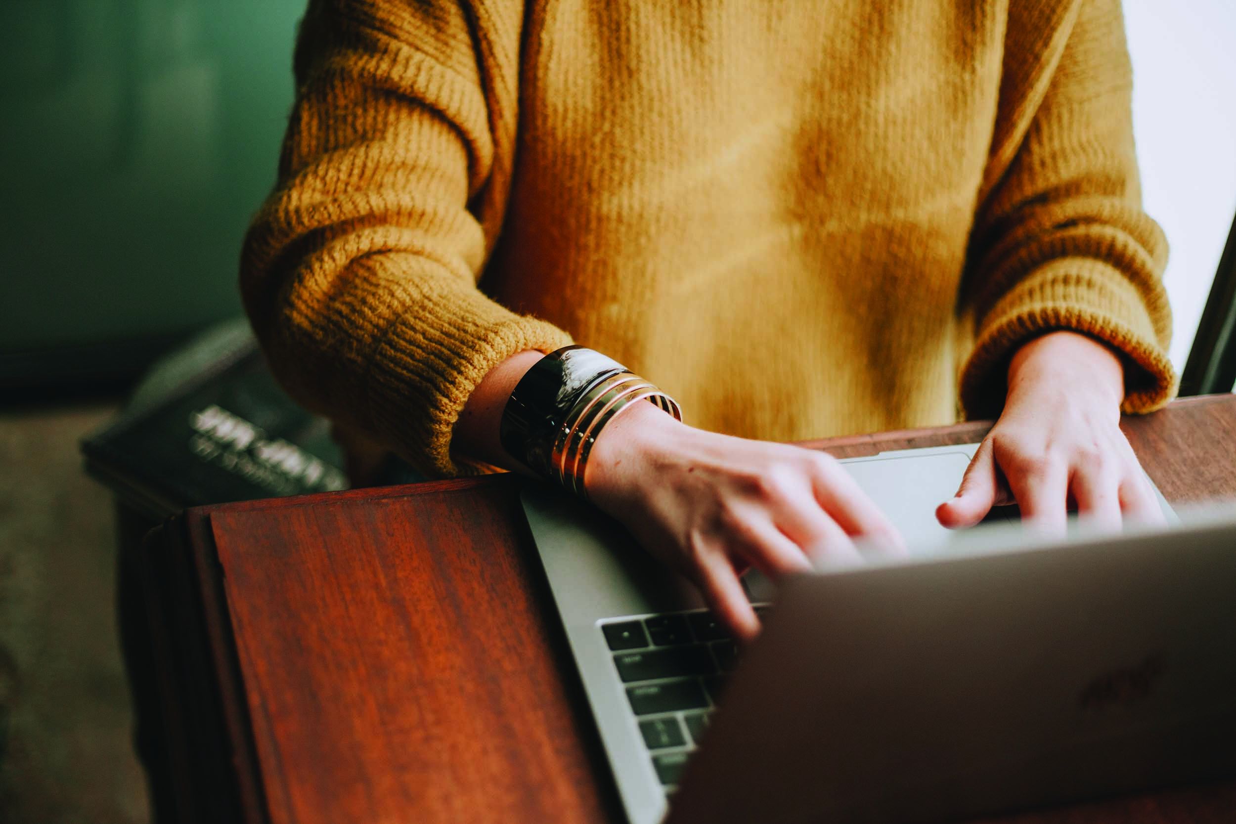 Bilde av en person som sitter ved et bord og skriver på en PC. Bilde av en person som sitter ved et bord og skriver på en PC.