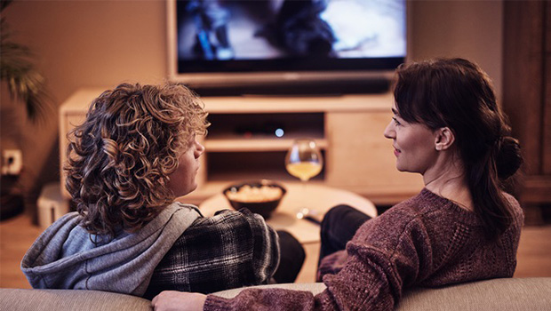 Et barn og en mor sitter sammen i en sofa foran en påskrudd TV
